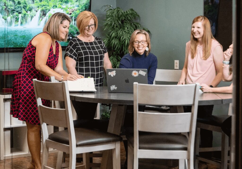 A group of women standing in front of a computer